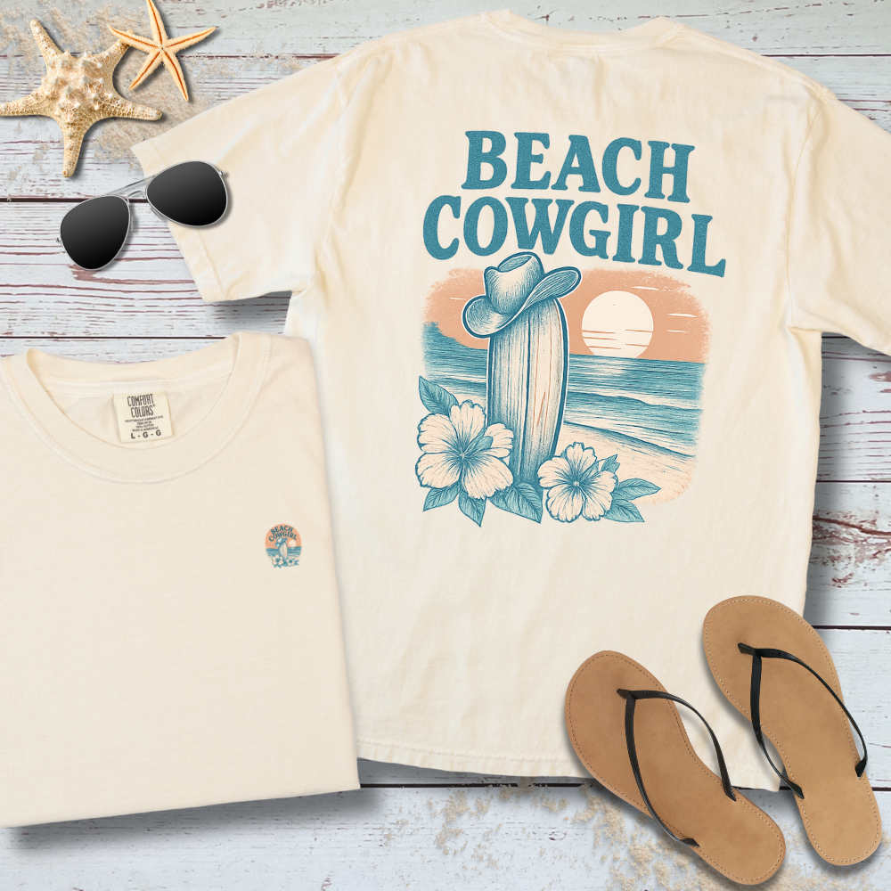 Beach-themed t-shirt with 'Beach Cowgirl' design on a wooden surface with sunglasses and flip-flops.